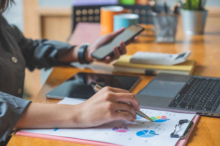 Cropped shot of young female entrepreneur hands analyzing financial report.の写真素材