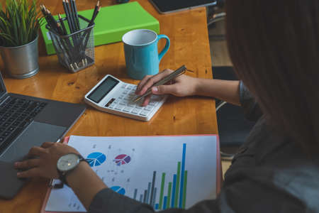 Cropped shot of young business woman analyzing financial report using calculatorの写真素材