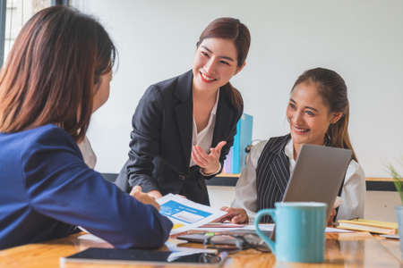 Focused cheerful female asian leader giving advise to colleague during meetingの写真素材