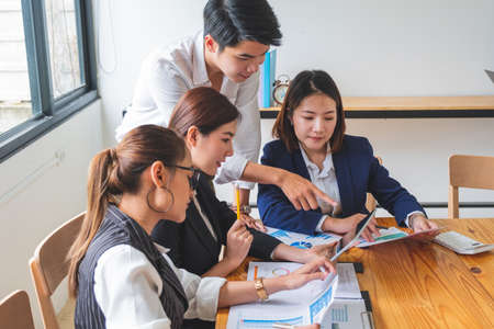 Young asian entrepreneurs in business casual analyzing financial in smart device