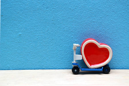 A large red heart on scooter, on a blue backdrop.の写真素材