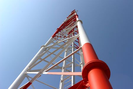 The telephone tower is white and red. View from bottom to top. Sky is background.