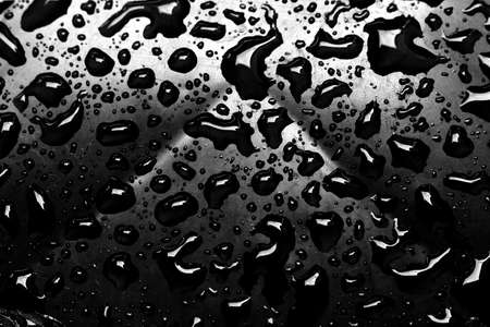 The falling rain leaves a beautiful pattern on a black background.の写真素材