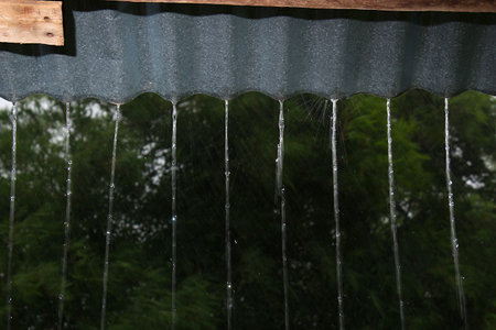 Rain falls from the roof made of zinc. Can be seen as a line coming down in an orderly row.