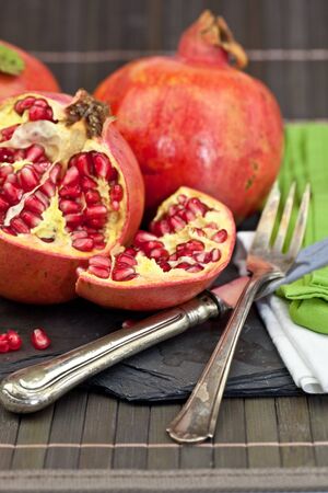 Fresh pomegranate with vintage silver cutleryの写真素材