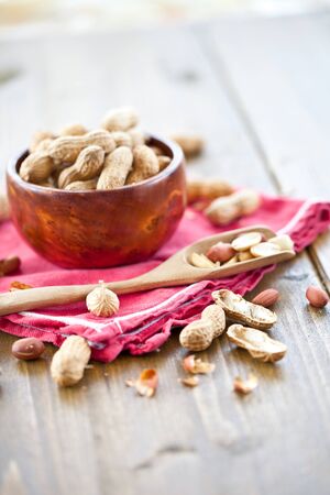 A wooden bowl filled with peanuts