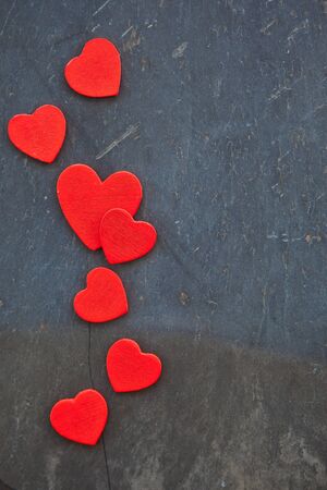 Dark stone background with red heartsの写真素材