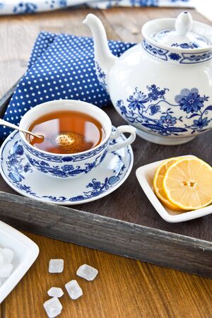 Hot tea with a slice of fresh lemon on a wooden trayの写真素材