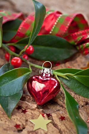 Christmas decorations and holly branches on rustic barkの写真素材
