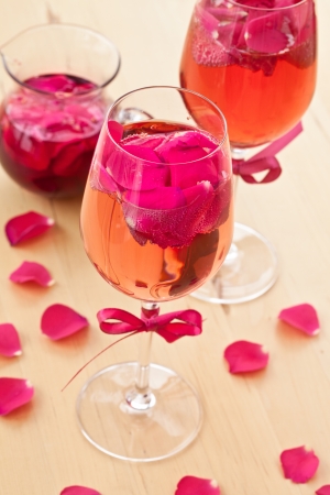 Pink Cocktail with fresh rose petals on wooden tableの写真素材