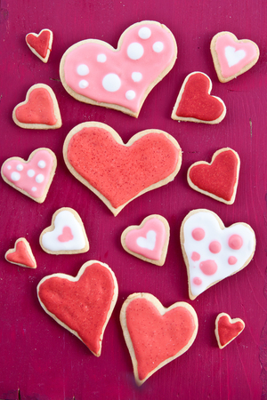 Colorful cookies in heart-shapes on red wooden backgroundの写真素材