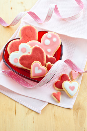 Colorful cookies in heart-shapes on red plateの写真素材