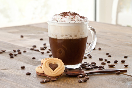 Cup of hot coffee with creamy milk foam and cookiesの写真素材