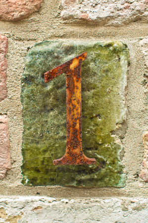 The number one made of rusty metall on a brick wallの写真素材