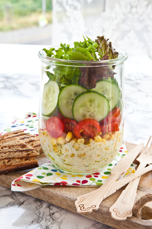 Layered salad with fresh vegetables in vintage jarの写真素材