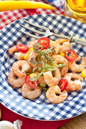 Garlic shrimps with chili peppers on a checkered plateの写真素材