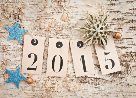2015 on paper tags on rustic wooden background with glittery stars