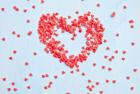 Red sugar sprinkles in heart shapes on blueの写真素材