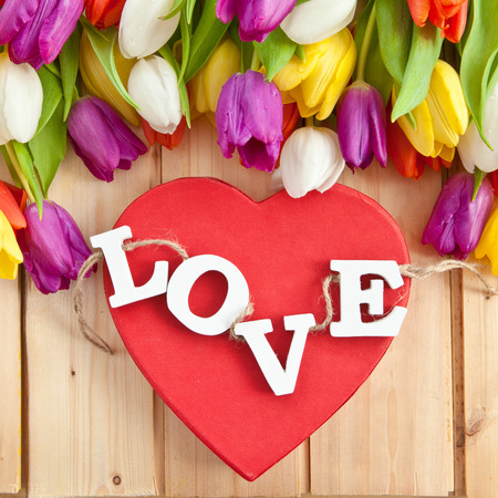 LOVE in wooden letters on red heart and fresh tulipsの写真素材