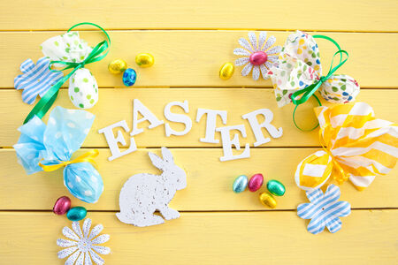 Colorful decorations for easter on yellow wooden background
