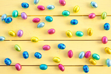Colorful chocolate eggs for easter  on yellow wooden boards