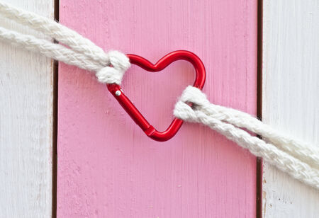 Red heartshaped snap link on rustic wooden backgroundの写真素材