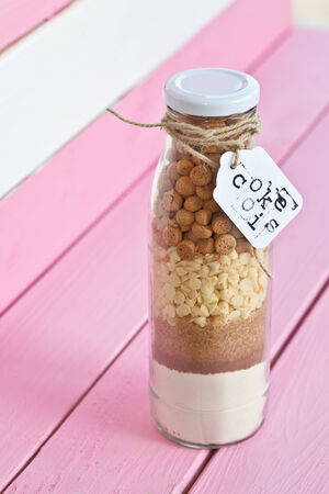 Vintage bottle with cookie mix on pink rustic boardsの写真素材