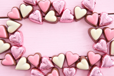 Colorful milk chocolates in heart-shapes on pinkの写真素材