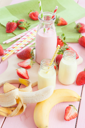 Vintage glass bottle with milk and fresh strawberries and bananasの写真素材