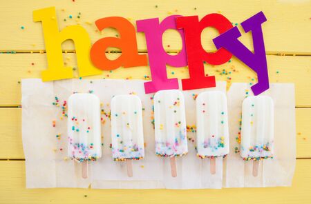 Homemade frozen vanilla popsicles with colorful sprinklesの写真素材