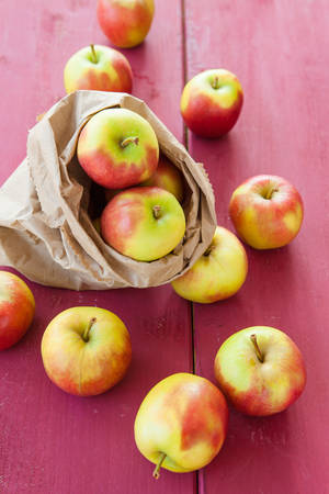 Fresh ripe apples in paper bag on wooden backgroundの写真素材