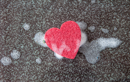 Red kitchen sponge in a heart shape on dark backgroundの写真素材