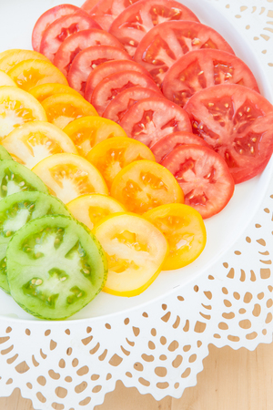 Slices of fresh organic red, green, and yellow tomatoesの写真素材