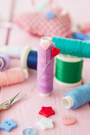 Sewing yarns pins and colorful buttons on pinkの写真素材