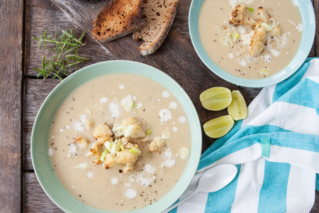 Plate of creamy soup with roasted cauliflower and spring onionsの写真素材