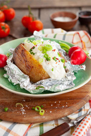 Baked potato with sour cream and fresh herbsの写真素材