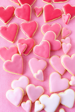 Little cookie hearts with pink icing on a pink backgroundの写真素材