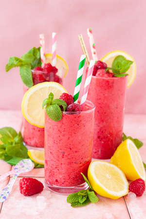 Frozen Smoothie, raspberry sherbet in glasses with fresh lemon and mintの写真素材