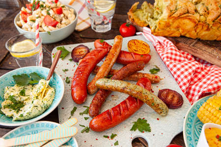 BBQ with grilled sausages, pasta salad and homemade breadの写真素材