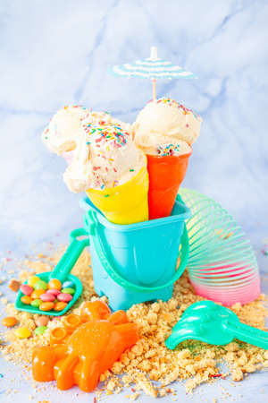 Vanilla ice cream with colorful sugar sprinkles with colorful beach toysの写真素材