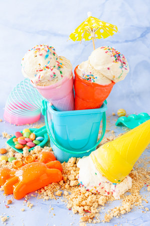 Vanilla ice cream with colorful sugar sprinkles with colorful beach toysの写真素材