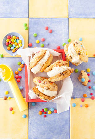Vanilla ice cream sandwich with chocolate chip cookies and colorful chocolate lentilsの写真素材