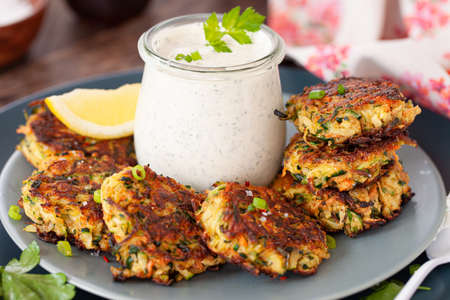 Savory zucchini vegetable fritters with a sour cream dipの写真素材