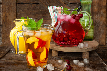 Ice cold beverages with fresh fruits in glass pitchersの写真素材