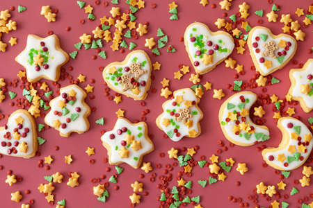 Colorful Christmas cookies with sugar sprinkles on a red backgroundの写真素材