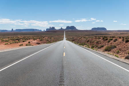 Route with a straight view to the most iconic view of Monument Valley National Park with a cloudless sky at Utah, United States. Some clouds can be seen on the horizonの写真素材