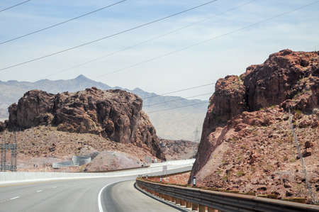 Winding highway in the middle of the Arizona desert near the Dam. some high power towers can be seen on the landscapeの写真素材