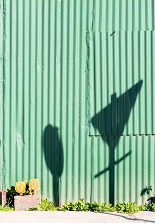 Shadow of a speed sign and yield sign over a green wall at Ushuaia, Tierra del Fuego, Argentinaの写真素材