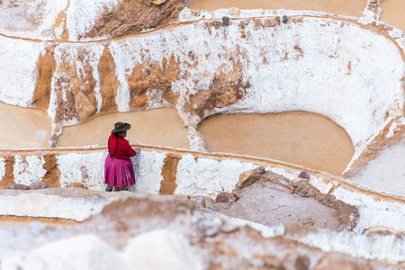 Woman extracting salt at Maras Peru. Woman on a colorful dress extracting salt at the salt terraces, called Maras, near Cusco, Peruの写真素材
