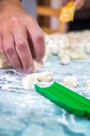 A lady cooking homemade gnocchi for lunch. The green toold to make then is in the foreground
